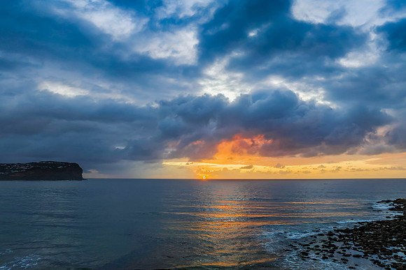 Drizzly moody sunrise seascape with cloud filled sky