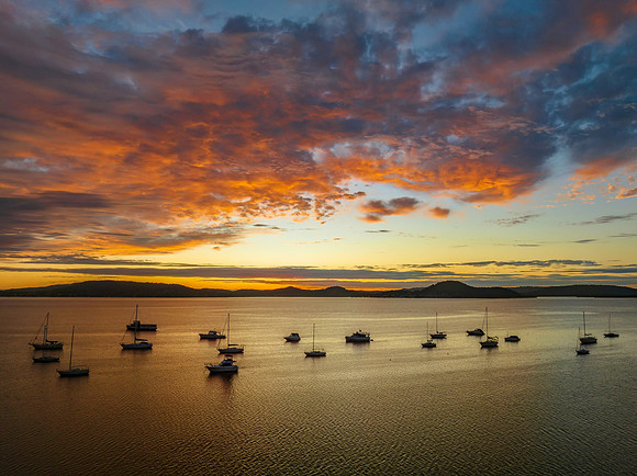 Aerial sunrise over the bay with boats and clouds