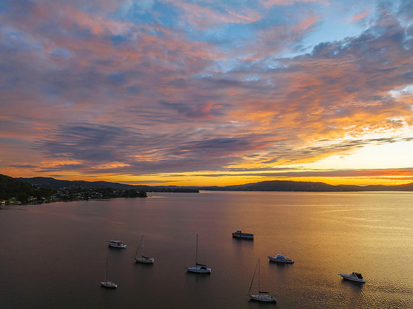 Aerial sunrise over the bay with boats and clouds
