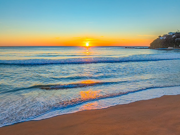 Ocean Sunrise Under Clear Skies with Orange Horizon