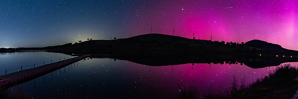 Aurora Australis display lights up the sky in pinks over the dam