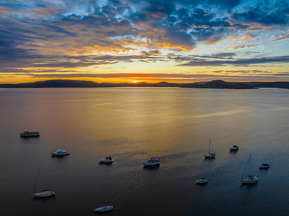 Aerial sunrise over the bay with boats and clouds