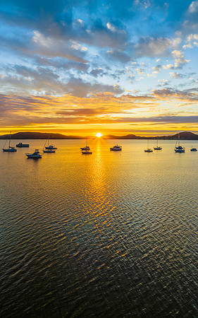 Aerial sunrise over the bay with boats, clouds and sunburst