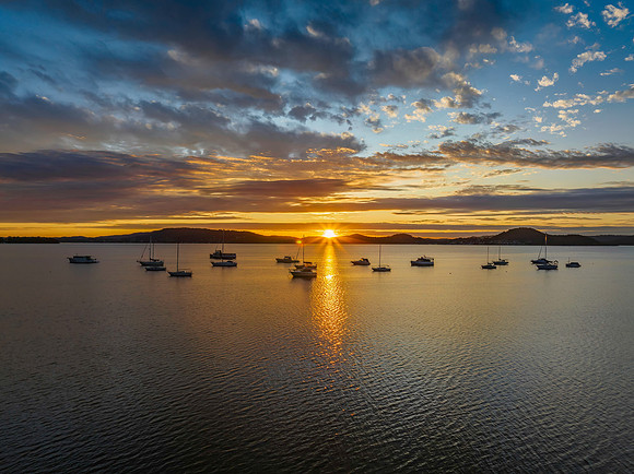 Aerial sunrise over the bay with boats, clouds and sunburst