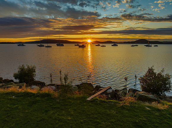 Aerial sunrise over the bay with boats, clouds and sunburst
