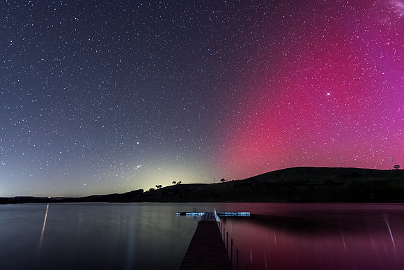 Aurora Australis display lights up the sky in pinks over the dam