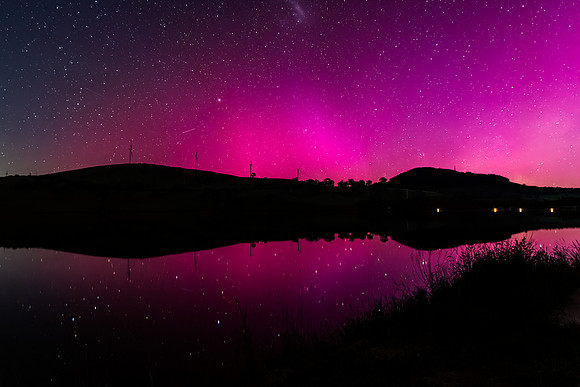 Aurora Australis display lights up the sky in pinks over the dam