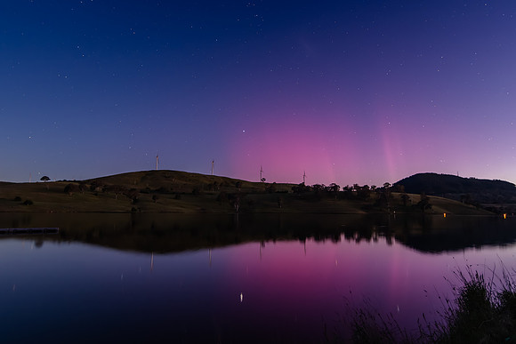 Aurora Australis display lights up the sky in pinks over the dam
