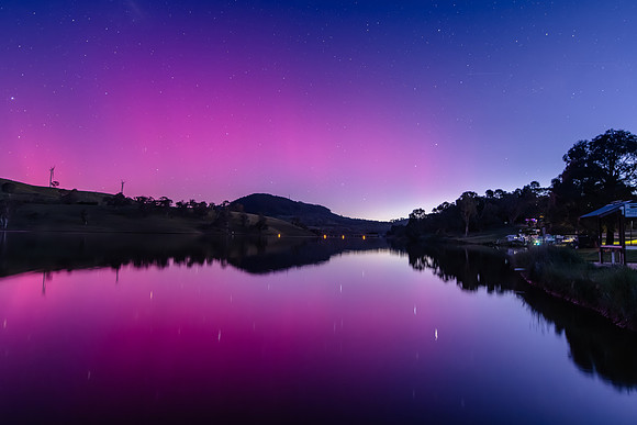 Aurora Australis display lights up the sky in pinks over the dam