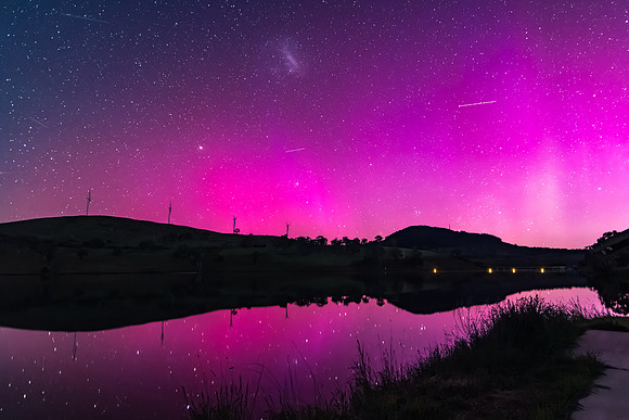 Aurora Australis display lights up the sky in pinks over the dam