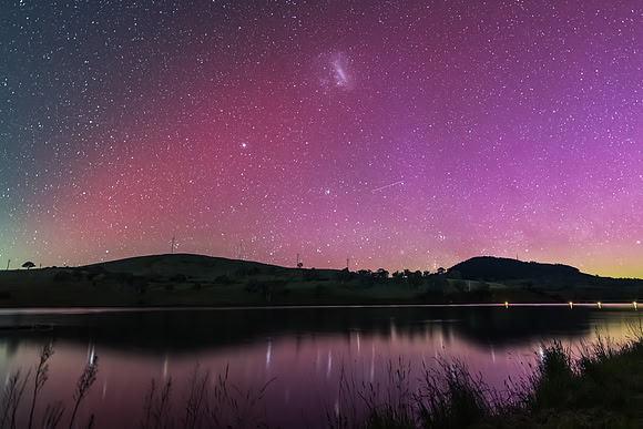 Aurora Australis display lights up the sky in pinks over the dam