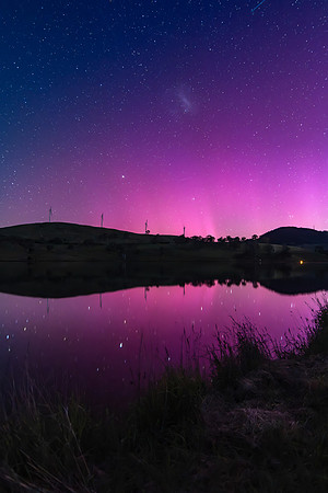 Aurora Australis display lights up the sky in pinks over the dam