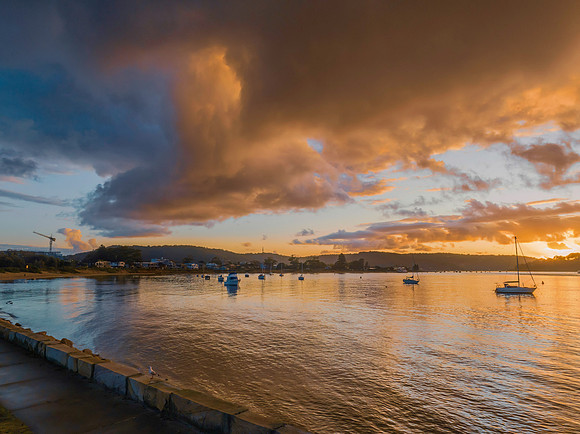 Aerial sunrise waterscape with boats and rain clouds