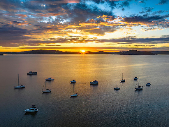 Aerial sunrise over the bay with boats, clouds and sunburst