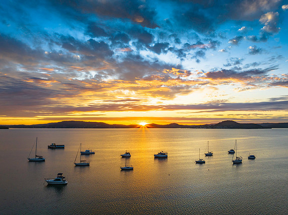 Aerial sunrise over the bay with boats, clouds and sunburst