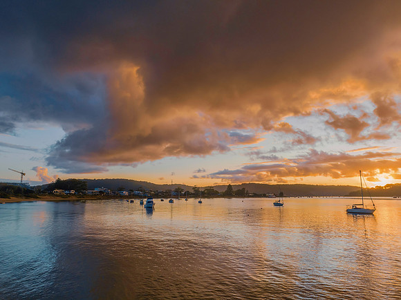 Aerial sunrise waterscape with boats and rain clouds