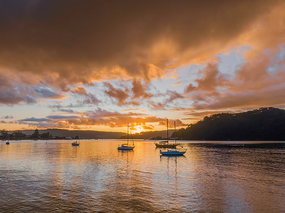 Aerial sunrise waterscape with boats and rain clouds