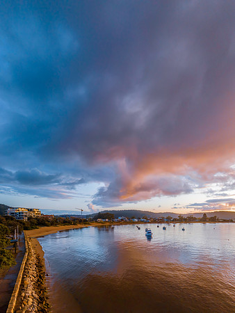 Aerial sunrise waterscape with boats and rain clouds