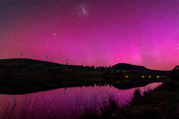 Aurora Australis display lights up the sky in pinks over the dam