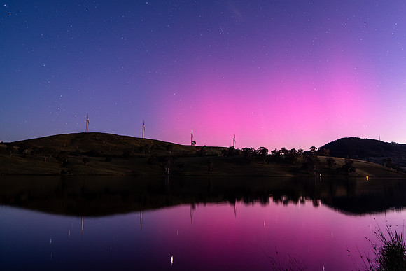 Aurora Australis display lights up the sky in pinks over the dam
