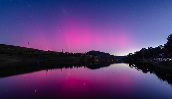 Aurora Australis display lights up the sky in pinks over the dam