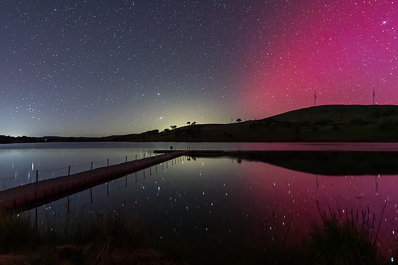 Aurora Australis display lights up the sky in pinks over the dam