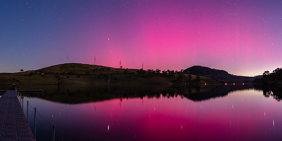 Aurora Australis display lights up the sky in pinks over the dam