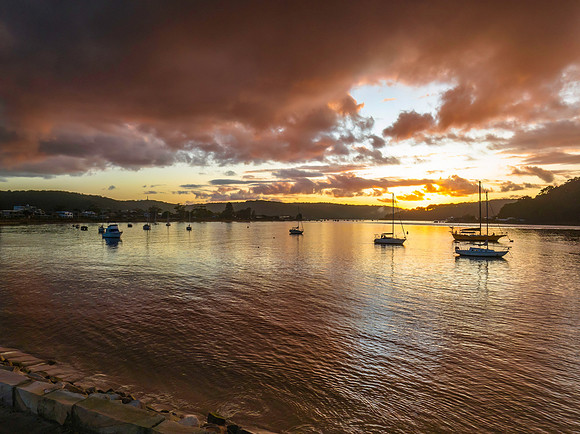 Aerial sunrise waterscape with boats and rain clouds
