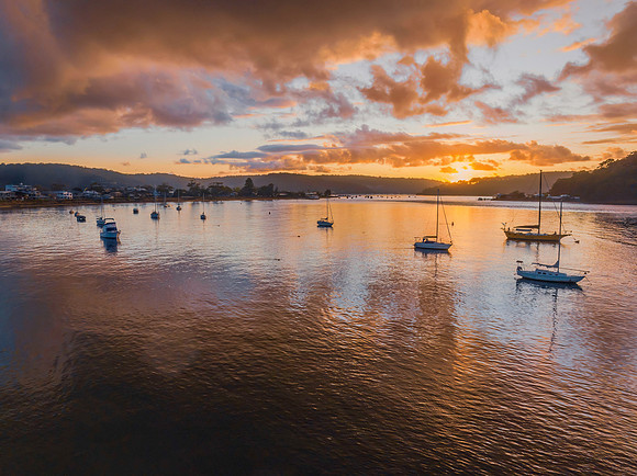 Aerial sunrise waterscape with boats and rain clouds