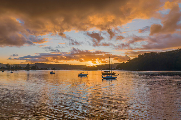 Aerial sunrise waterscape with boats and rain clouds