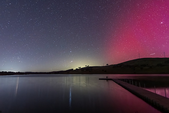 Aurora Australis display lights up the sky in pinks over the dam