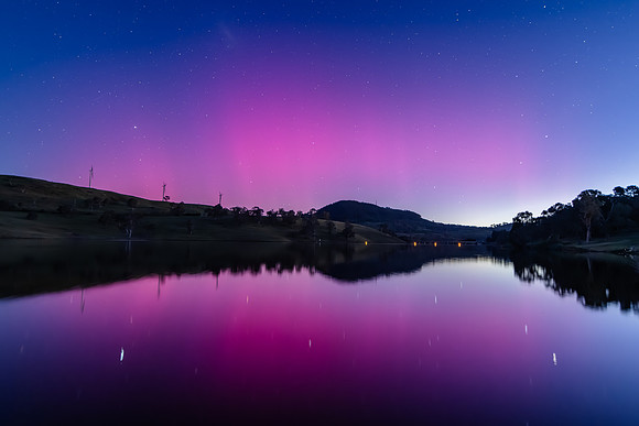 Aurora Australis display lights up the sky in pinks over the dam