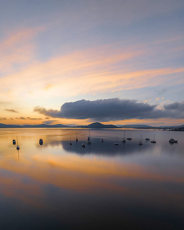 Sunrise over the water with fog, boats, clouds and reflections