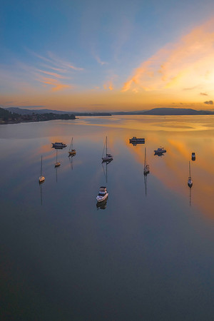 Sunrise over the water with fog, boats, clouds and reflections