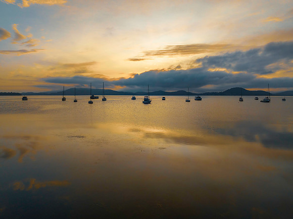 Sunrise over the water with fog, boats, clouds and reflections
