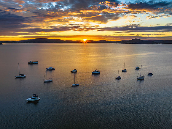 Aerial sunrise over the bay with boats, clouds and sunburst