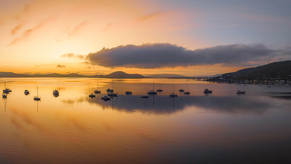 Sunrise over the water with fog, boats, clouds and reflections