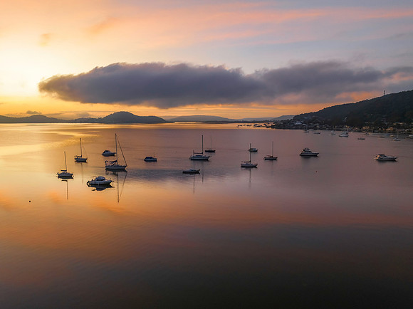 Sunrise over the water with fog, boats, clouds and reflections