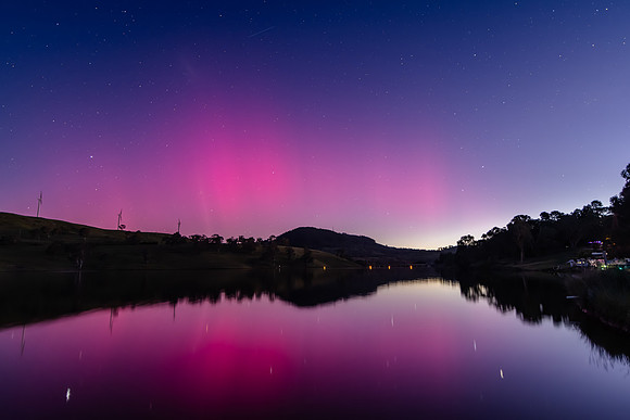 Aurora Australis display lights up the sky in pinks over the dam