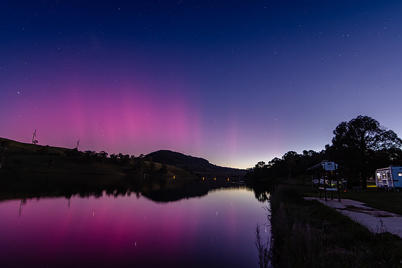 Aurora Australis display lights up the sky in pinks over the dam