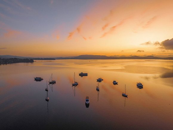 Sunrise over the water with fog, boats, clouds and reflections