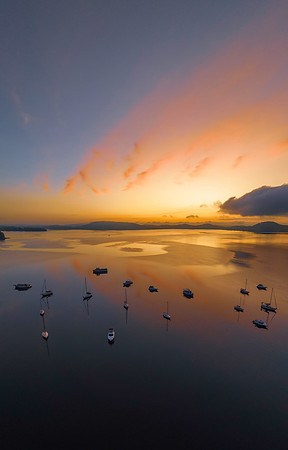 Sunrise over the water with fog, boats, clouds and reflections