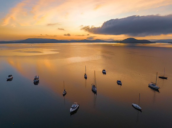 Sunrise over the water with fog, boats, clouds and reflections