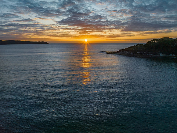 Aerial sunrise seascape with calm seas and a mix of low and medi
