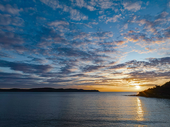Aerial sunrise seascape with calm seas and a mix of low and medi