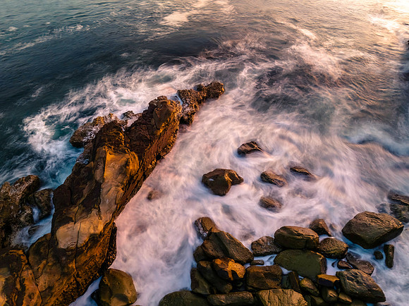 Top down sunrise over the ocean with rocks