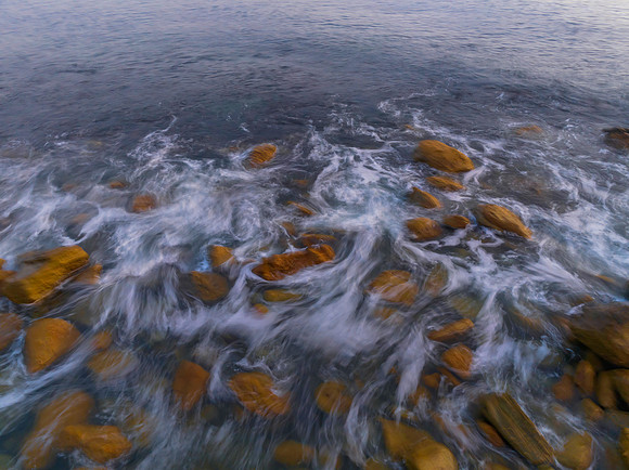 Top down sunrise over the ocean with rocks
