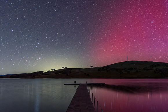Aurora Australis display lights up the sky in pinks over the dam