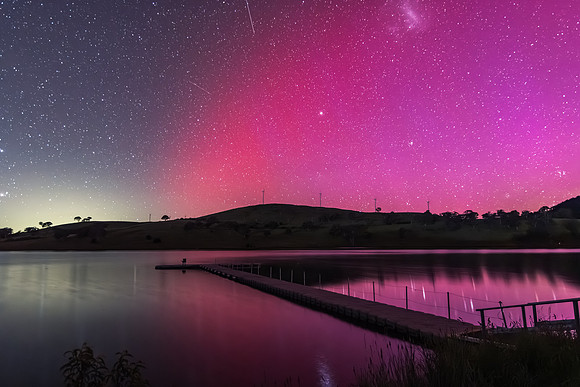 Aurora Australis display lights up the sky in pinks over the dam
