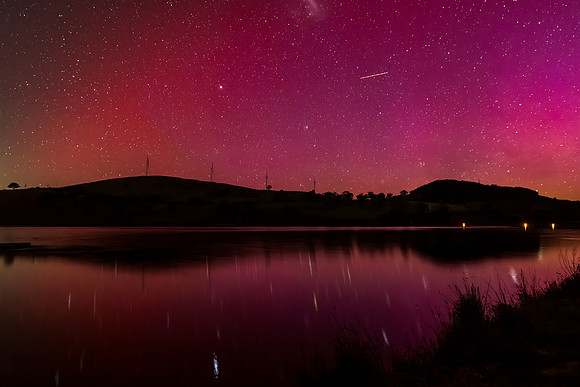Aurora Australis display lights up the sky in pinks over the dam